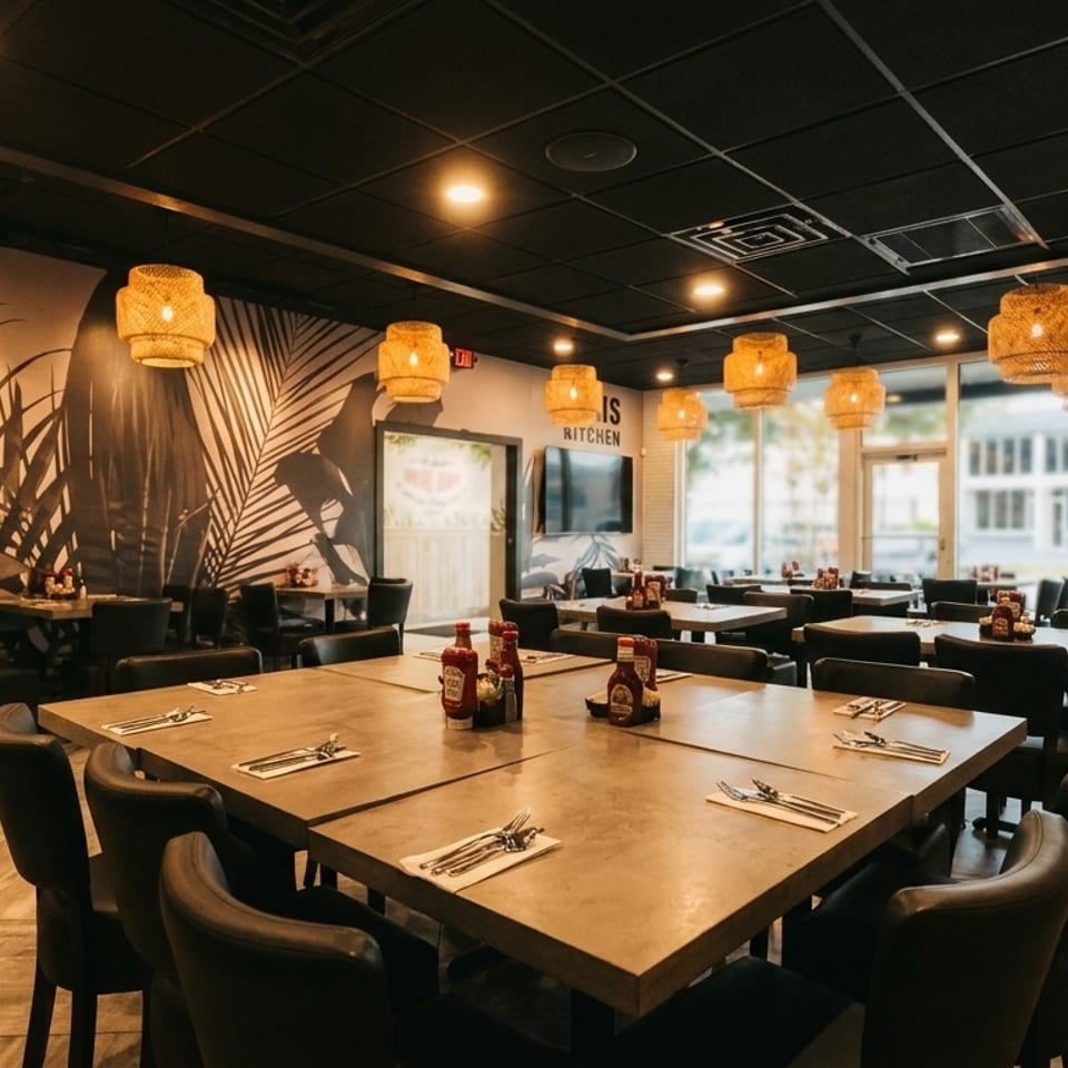 Modern restaurant interior with dark tables, black chairs, woven light fixtures, and tropical leaf wallpaper.