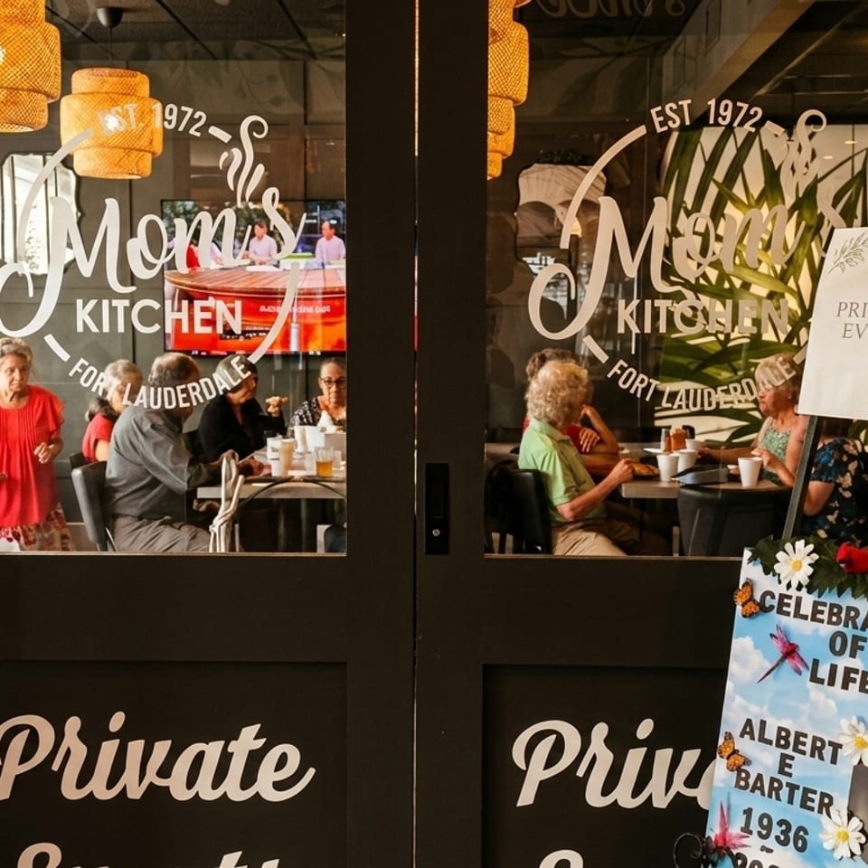 Restaurant patrons seated at tables inside Mom's Kitchen, viewed through glass doors with a "Private Event" sign.